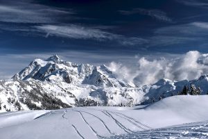 ski tracks on fresh powder snow with high mountains peaks in distance
