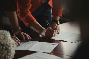 person-in-orange-long-sleeve-shirt-writing-on-white-paper
